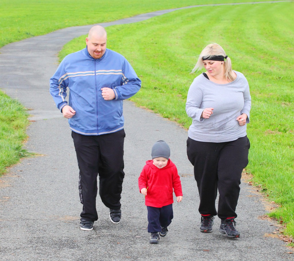 Overweight parents with her son running together.