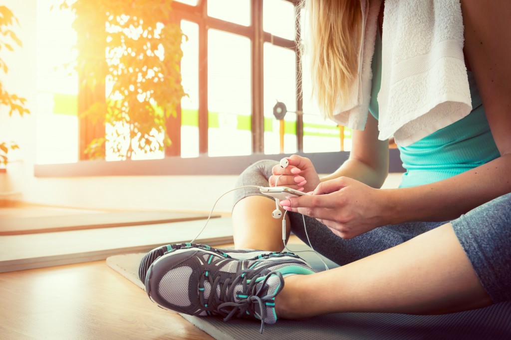 Attractive blond woman with smart phone, resting after gym workout